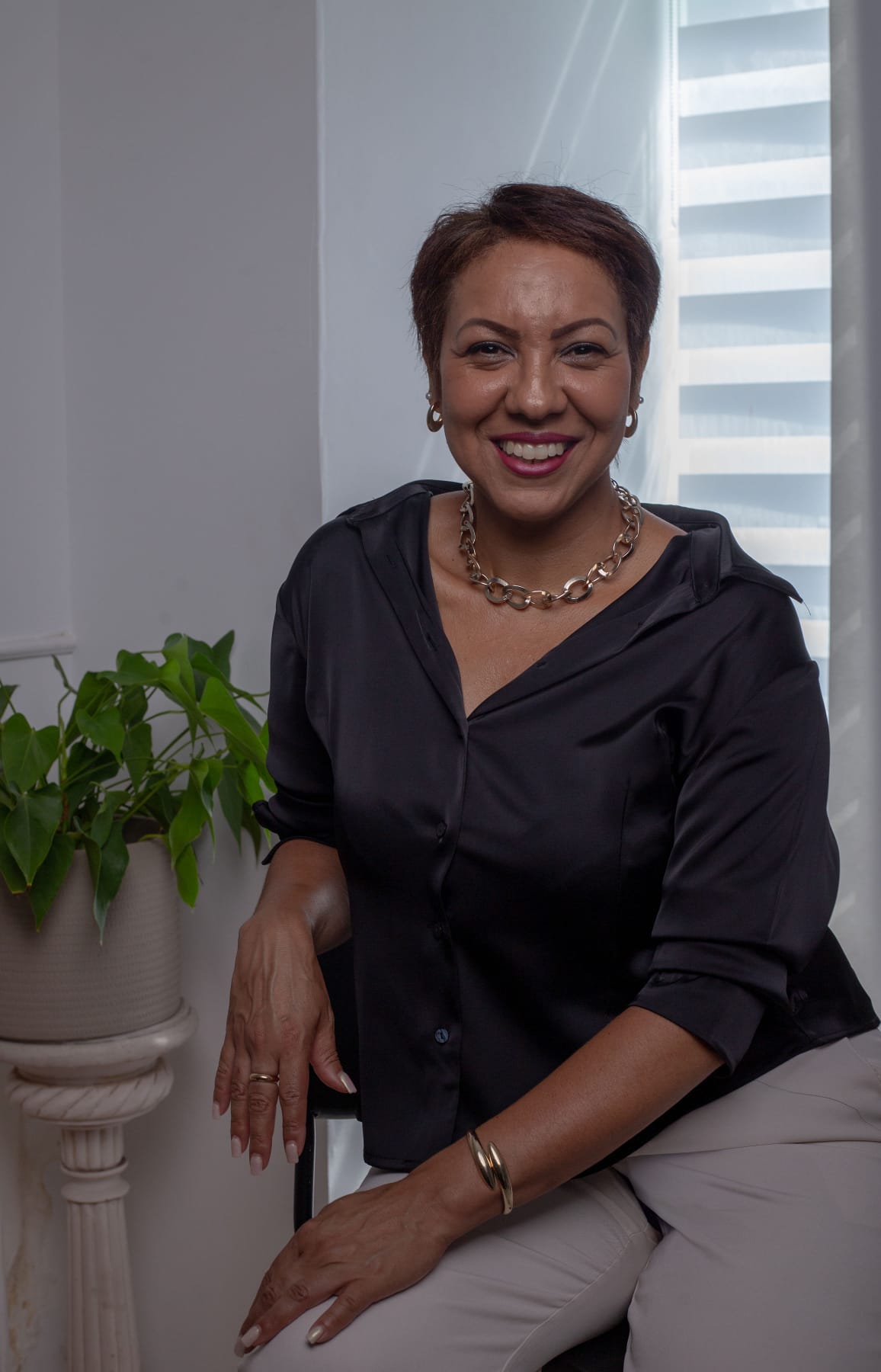 Cris Rodrigues sorrindo, sentada junto à janela